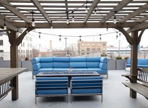 a patio with a blue couch and tables and benches at Kasa Downtown Salt Lake City in Salt Lake City