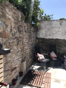 un patio con 2 sillas y una pared de piedra en Casa do Mercador by Portus Alacer, en Avis