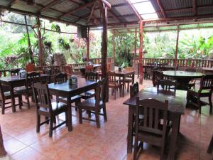 un restaurante con mesas de madera, sillas y árboles en Casita Lidia Bijagua, en Bijagua