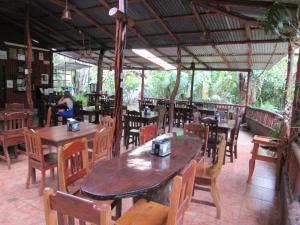 un restaurante con mesas de madera y sillas de madera en Casita Lidia Bijagua, en Bijagua