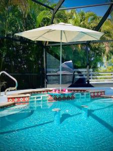 een zwembad met een parasol en een zwembad bij Casa de Emma - a 3-bed gulf access vacation home in Cape Coral