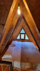 a bed in a attic with a window at Bungaja Chalets in Shkodër