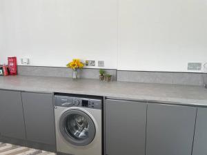 a kitchen with a washing machine under a counter at Fantastic home in Brightons, Falkirk. in Polmont