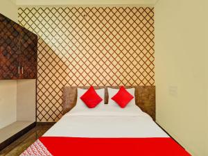 a bedroom with a bed with red pillows on it at OYO Flagship Mathrushree Lodge in Yelahanka