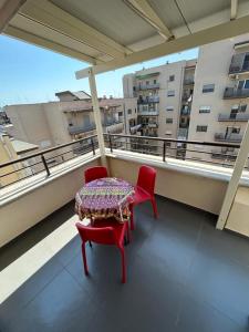 a table and two red chairs on a balcony at Attico Stazione - Montello 16 in Bari