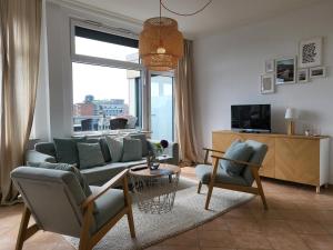 een woonkamer met een bank en stoelen en een tv bij Penthousewohnung 66 im Haus Villa Anna in Sankt Peter-Ording