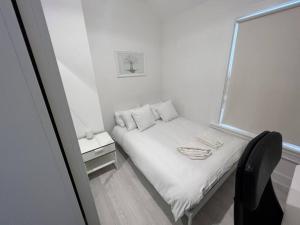 ein kleines Schlafzimmer mit einem weißen Bett und einem Stuhl in der Unterkunft The Trinity College Townhouse in Dublin