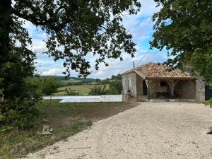 um pequeno edifício de pedra no meio de um campo em Maison charmante nature piscine chauffée em Montlauzun