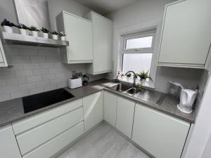 eine Küche mit weißen Schränken und einer Spüle und einem Fenster in der Unterkunft The Trinity College Townhouse in Dublin + 6 Fotos