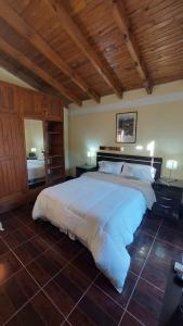 a large white bed in a bedroom with wooden ceilings at Posada del Carruaje in Santa Rosa de Calamuchita