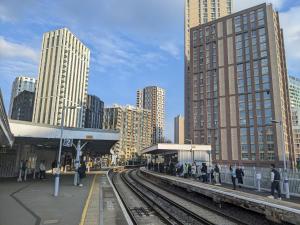 a train station with people waiting on the tracks at Luxury 1Bed Holiday Flat-10 Minutes from London Bridge & 3Mins walk to Lewisham DLR in London