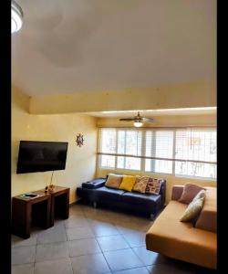 a living room with a couch and a flat screen tv at Cozy Condo in Costambar Beach in San Felipe de Puerto Plata