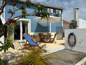 une maison bleue avec une table et un parasol dans l'établissement Villa Populo, à Ponta Delgada