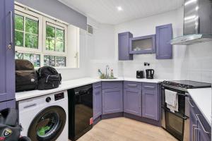 een keuken met paarse kasten en een wasmachine bij APlaceToStay Central London Apartment, Waterloo (UPT) in Londen