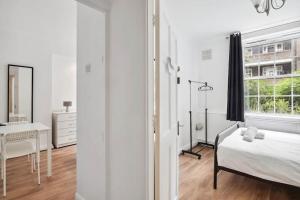 a white bedroom with a bed and a desk and a window at APlaceToStay Central London Apartment, Waterloo (UPT) in London
