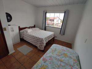 a small bedroom with a bed and a window at Casa aconchegante a 4km-5min da Guarda do Embaú in Guarda do Embaú