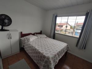 a bedroom with a bed and a window at Casa aconchegante a 4km-5min da Guarda do Embaú in Guarda do Embaú