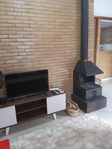 sala de estar con TV y chimenea en Chalés Bem-me-quer Itaipava, en Itaipava