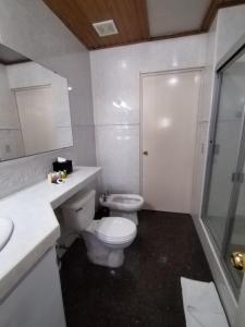 La salle de bains blanche est pourvue de toilettes et d'un lavabo. dans l'établissement Cardedeu Suites, à San Salvador