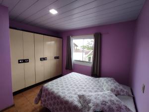 a bedroom with purple walls and a bed and a window at Casa aconchegante a 4km-5min da Guarda do Embaú in Guarda do Embaú