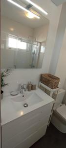 La salle de bains blanche est pourvue d'un lavabo et d'un miroir. dans l'établissement EnSAN CIPRIÁN Faro de Punta Atalaya, à Cervo