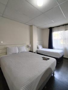 a bedroom with two beds and a window at Cardedeu Suites in San Salvador