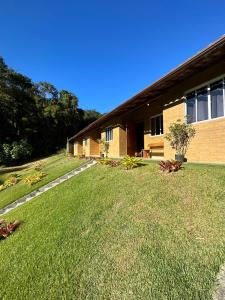 a house with a grass yard next to a building at Chalés Bem-me-quer Itaipava in Itaipava +73 photos