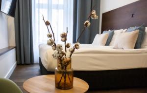 a vase with flowers on a table in a bedroom at Apartamenty Sowa Toruń in Toruń