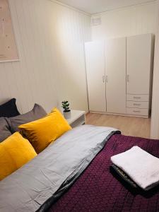 1 dormitorio con 1 cama con almohadas amarillas y armario en Oslo airport 15 en Nannestad