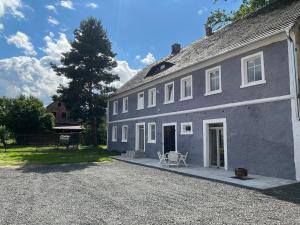 a large gray building with a gravel driveway at Polana Gorska Mirsk in Mirsk