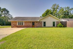 a house with a grass yard in front of it at Inviting Gulfport Home with Private Pool and Yard in Gulfport