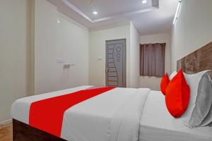 a bedroom with a white and red bed with red pillows at Flagship Hotel R Square Bn Reddy in Hyderabad