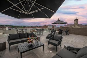 a rooftop patio with couches and tables and an umbrella at The Bee Hotel, Danville in Danville