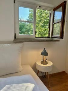 a bedroom with two windows and a table with a lamp at Apartment Huberspitz - Ruhe, Berge & Natur in Hausham