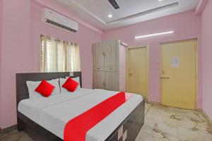 1 dormitorio con 1 cama grande con almohadas rojas en OYO Flagship Anu prime suites en Hyderabad