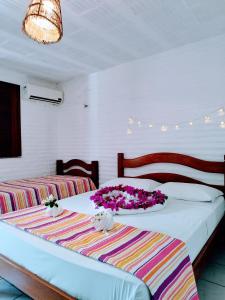 1 dormitorio con 2 camas con flores en Pousada Roane - Taíba, en Taíba