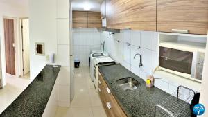a small kitchen with a sink and a microwave at Vacanze - Ametista 7 in Maceió
