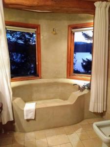 a bath tub in a bathroom with two windows at Punta Manzano in Villa La Angostura