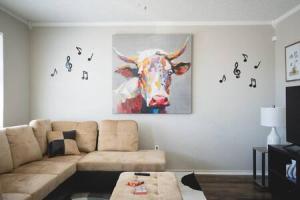 salon z kanapą i obrazem krowy w obiekcie La Palma Lodge Near Texas Tech and Top Restaurants w mieście Lubbock