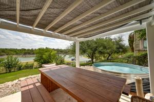 a patio with a wooden table and a swimming pool at Luxury Lakefront Home-Private Dock - Dipping Pool! in Spicewood