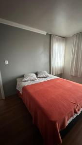 a bedroom with a bed with a red blanket at Apartamentos na região Central Cobertura e 2 quartos in Ponta Grossa