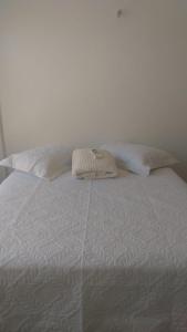 a white bed with two pillows on top of it at Salinas Atalaia -Flats Vale Di Serena in Salinópolis