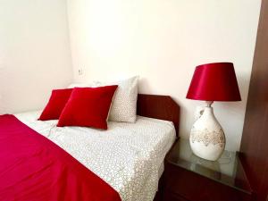 a bed with red pillows and a red lamp on a glass table at Apartment Adel in Mostar