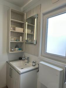 La salle de bains est pourvue d'un lavabo et d'une fenêtre. dans l'établissement Ahoi Haus Duo, à Drage