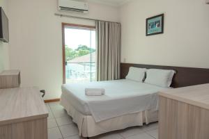 um quarto com uma cama grande e uma janela em Hotel Equinocios Executive em Barcarena