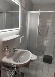 bagno bianco con lavandino e doccia di Landhaus Bichlbach a Bichlbach