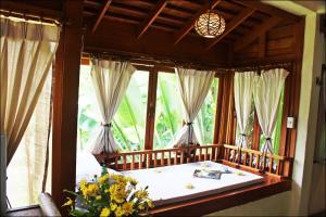 a bedroom with a large window with a bath tub at Pai Vimaan Resort in Pai