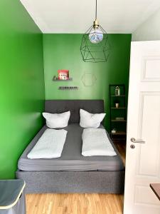 um quarto com paredes verdes e uma cama com almofadas brancas em Cozy, zentrumsnahe 2-Raumwohnung em Leipzig