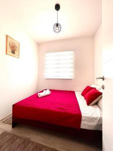 a bedroom with a red bed and a window at Apartment Adel in Mostar