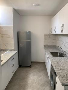 a small kitchen with a refrigerator and a sink at MTL residence in Oujda